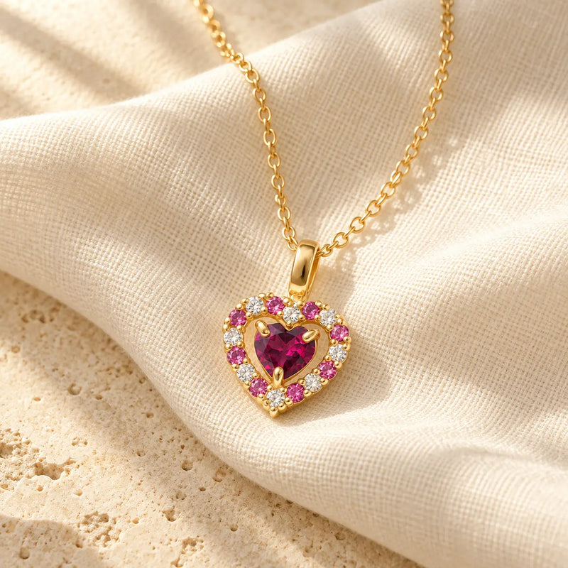 Rhodolite garnet heart pendant necklace in gold vermeil resting on ivory linen in warm natural light.