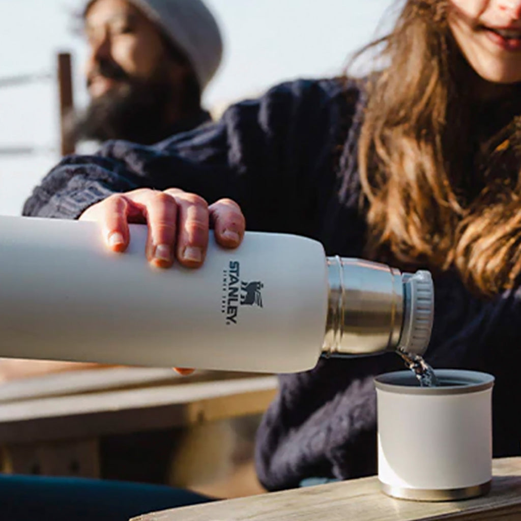 Stanley Adventure To Go 1.0L water bottle in stainless steel with black lid and carrying handle, designed for outdoor hydration.