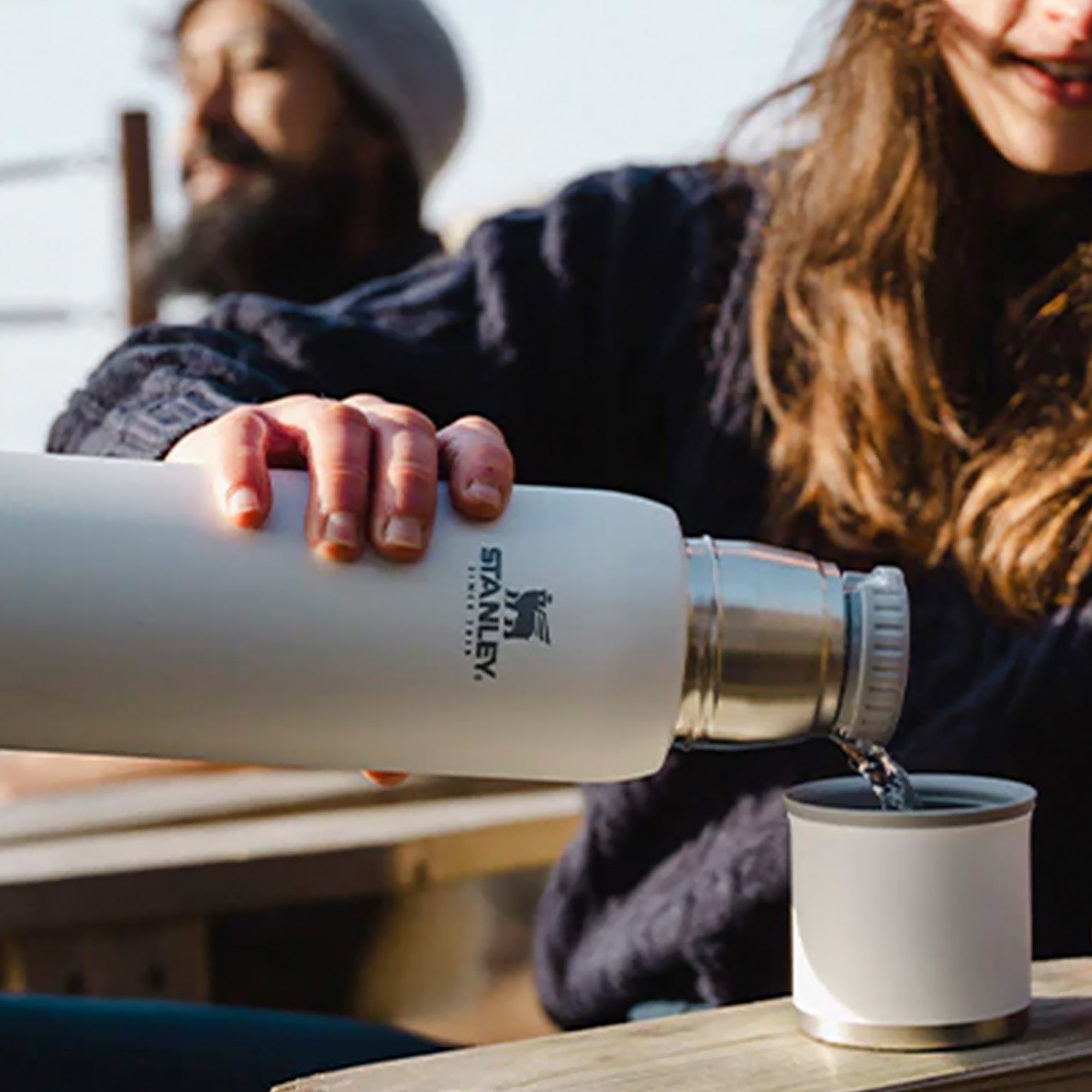 Stanley Adventure To Go 1.0L water bottle in stainless steel with black lid and carrying handle, designed for outdoor hydration.