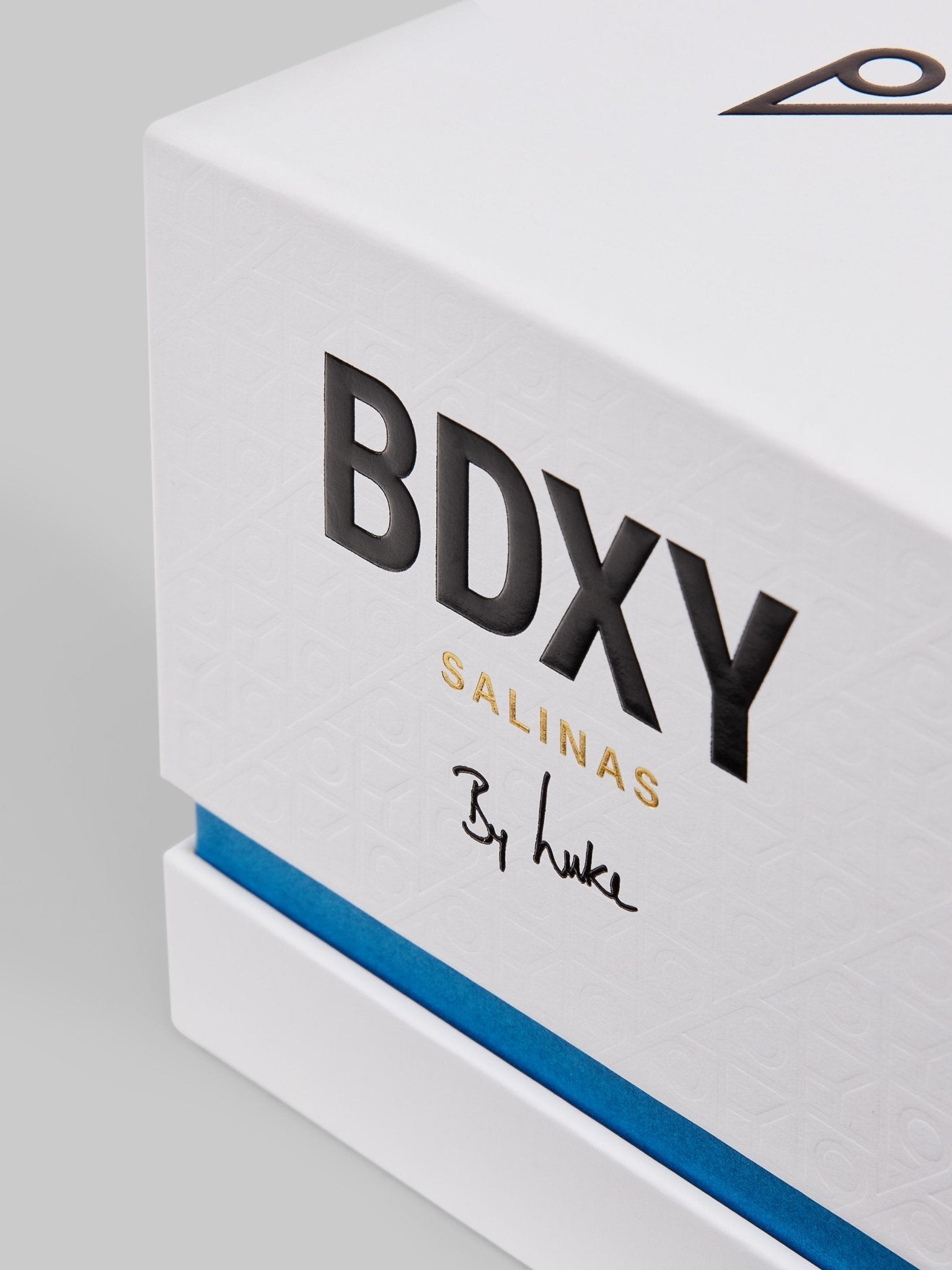 BDXY Studios scented candle from Salinas with a white ceramic holder and a lit wick, emitting a warm glow and subtle fragrance.
