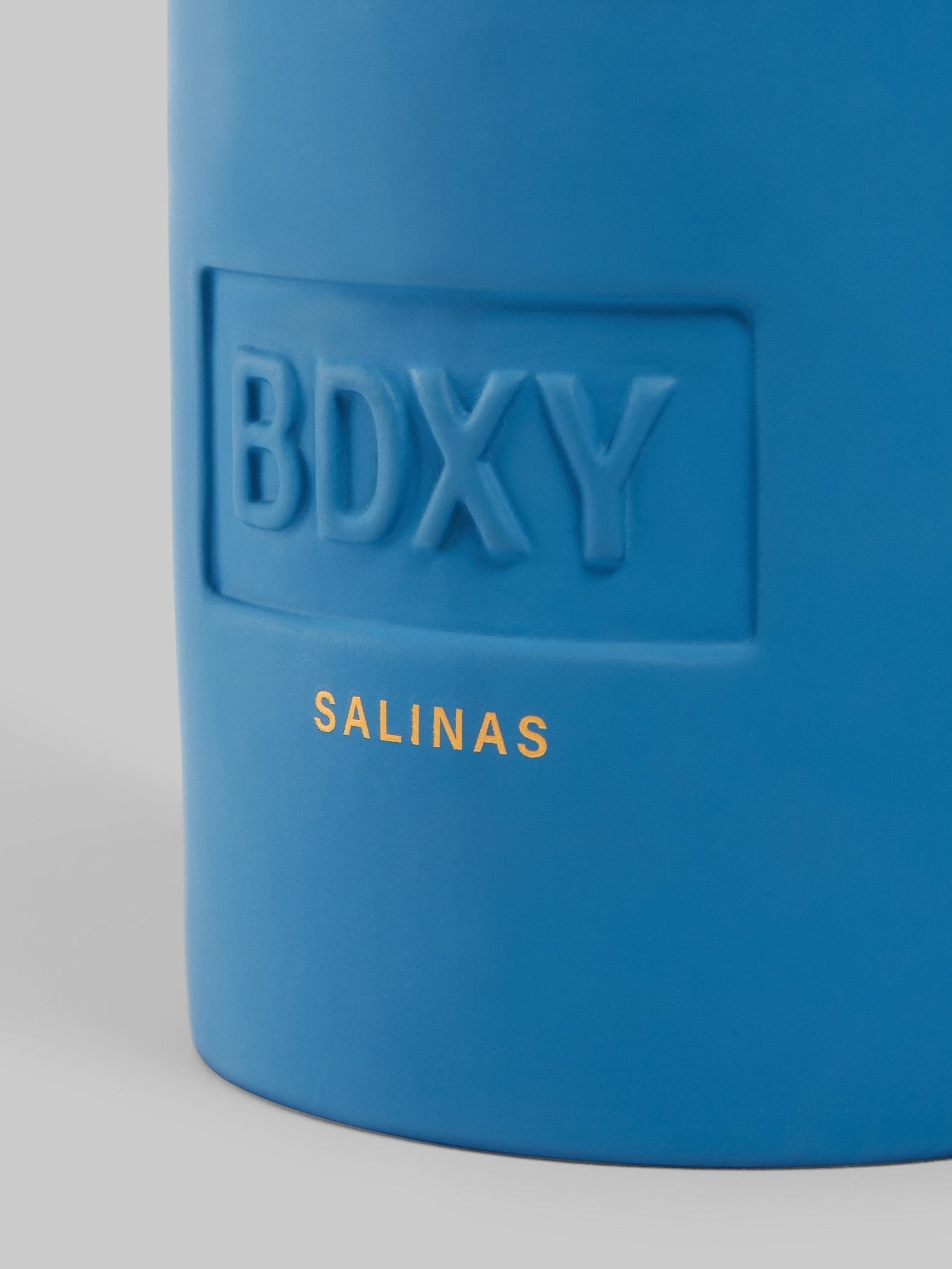 BDXY Studios scented candle with a minimalist design, displayed on a wooden surface with a soft, warm glow.