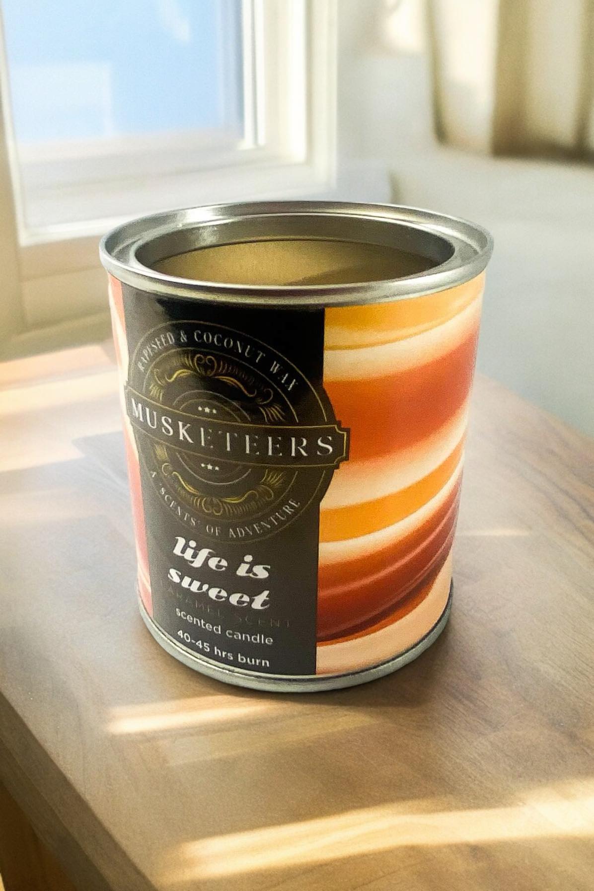 Musketeers Life is Sweet caramel candle with a warm, inviting glow and decorative label, perfect for cozy home decor.