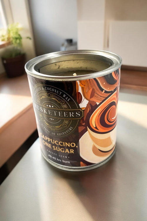 Musketeers coffee candle labeled Cappuccino with 1 sugar, featuring a realistic coffee cup design and warm, inviting tones.