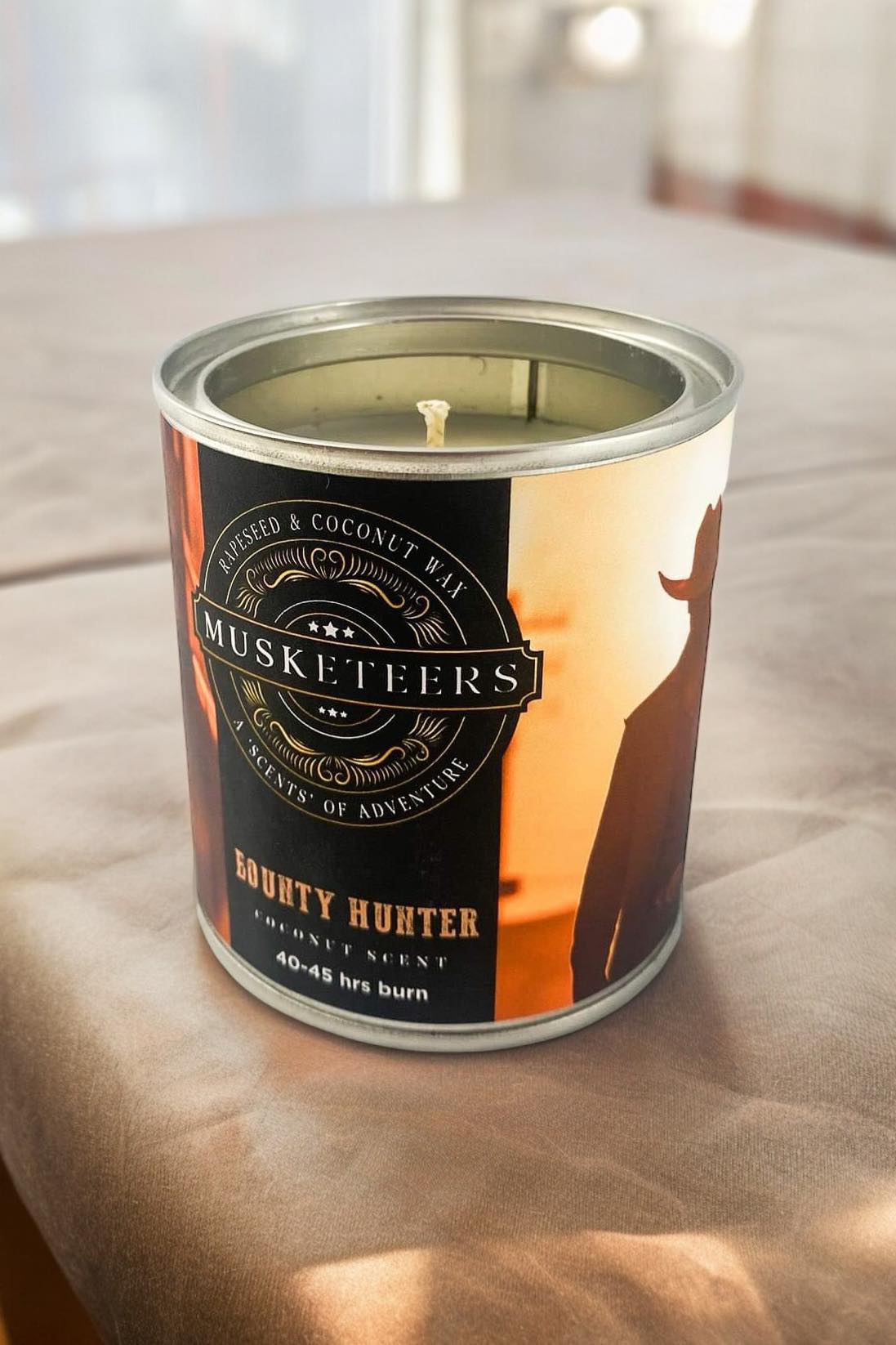 Musketeers Bounty Hunter coconut scented candle in a glass jar, with a warm, inviting glow and tropical coconut fragrance.