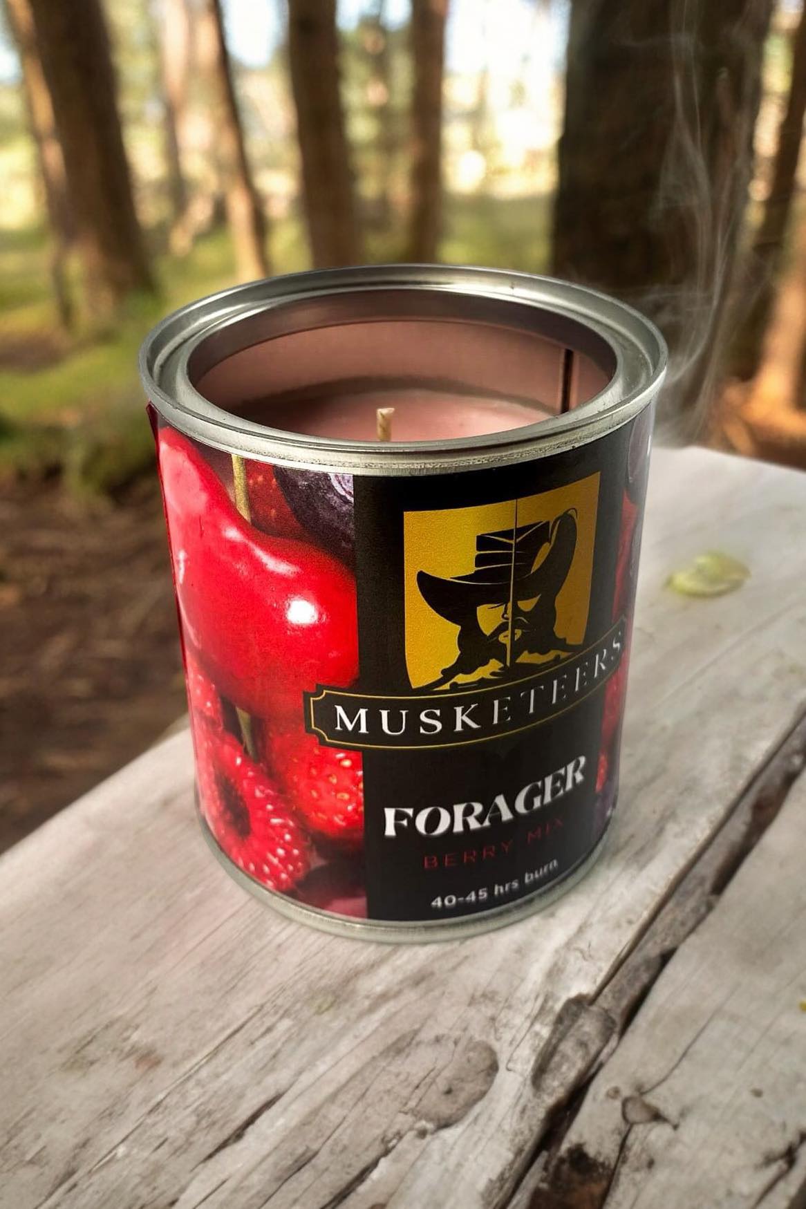 Musketeers Forager Berry Mix Candle burning in a glass jar with fresh berries and herbs, highlighting the natural, fruity scent.