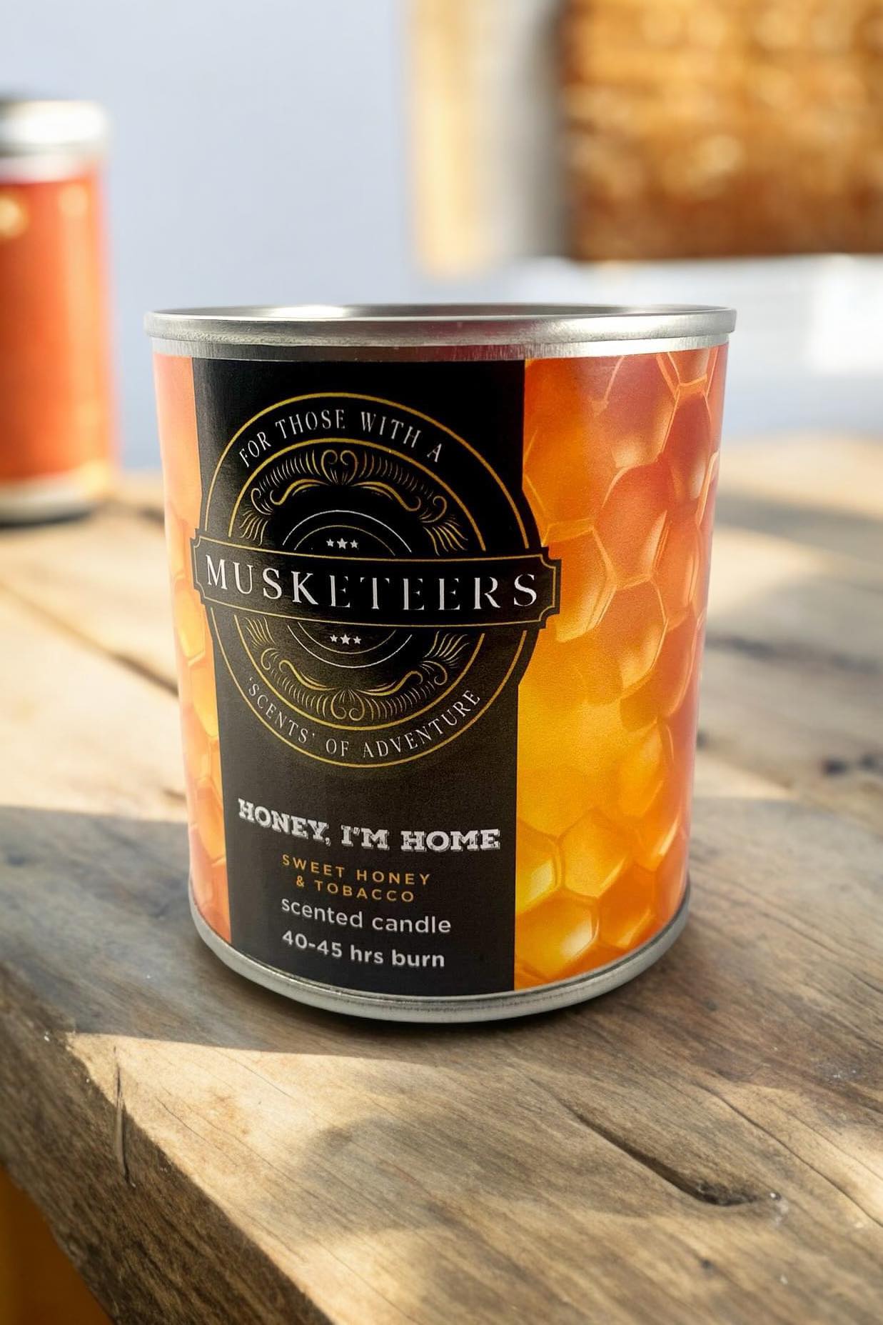 Musketeers Honey I'm Home candle with honey and tobacco scent, featuring a cozy, warm-colored wax in a glass jar.