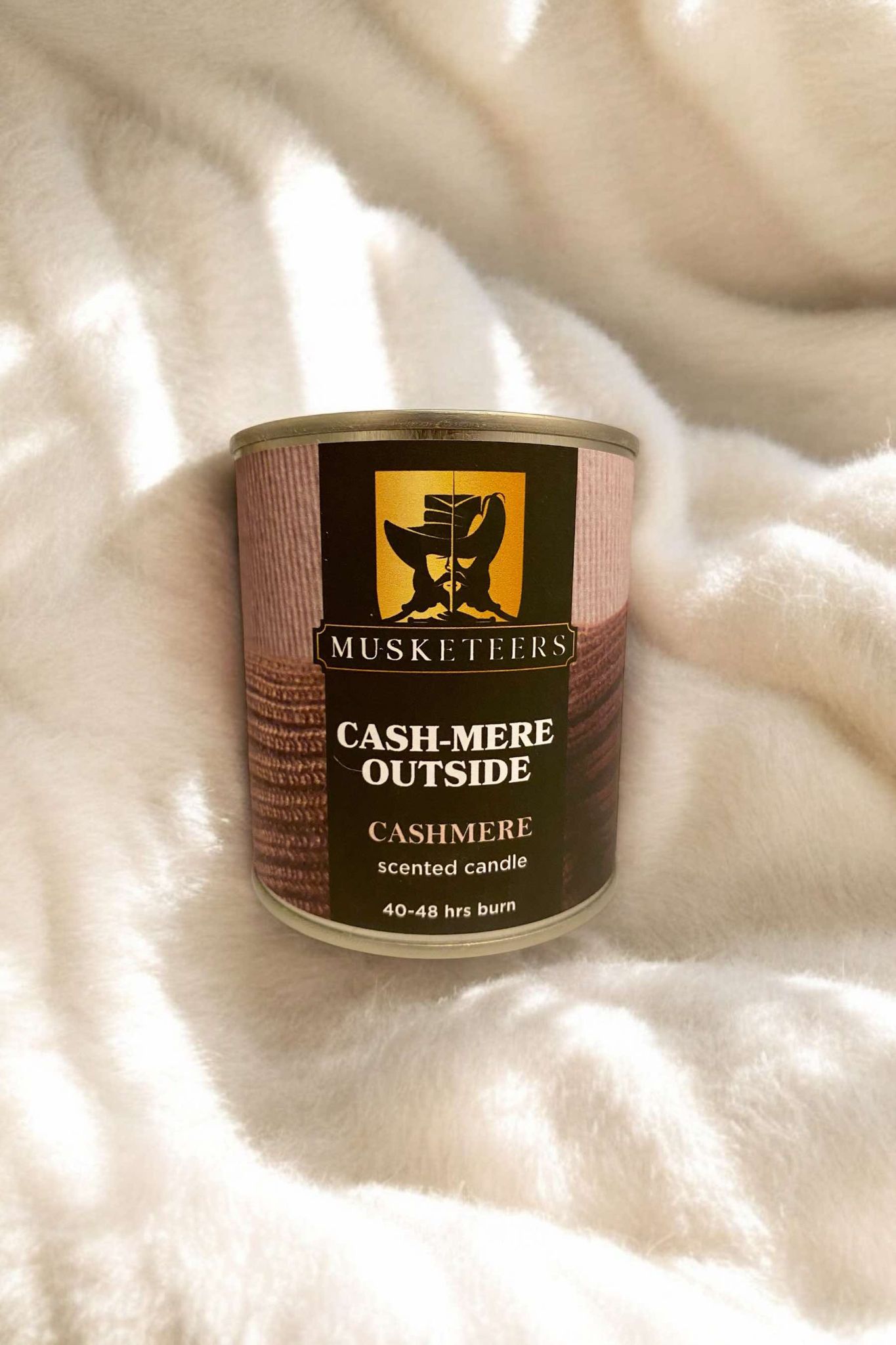 Musketeers cashmere scented candle in a glass holder, showcasing the elegant candle with soft glow and luxurious design.