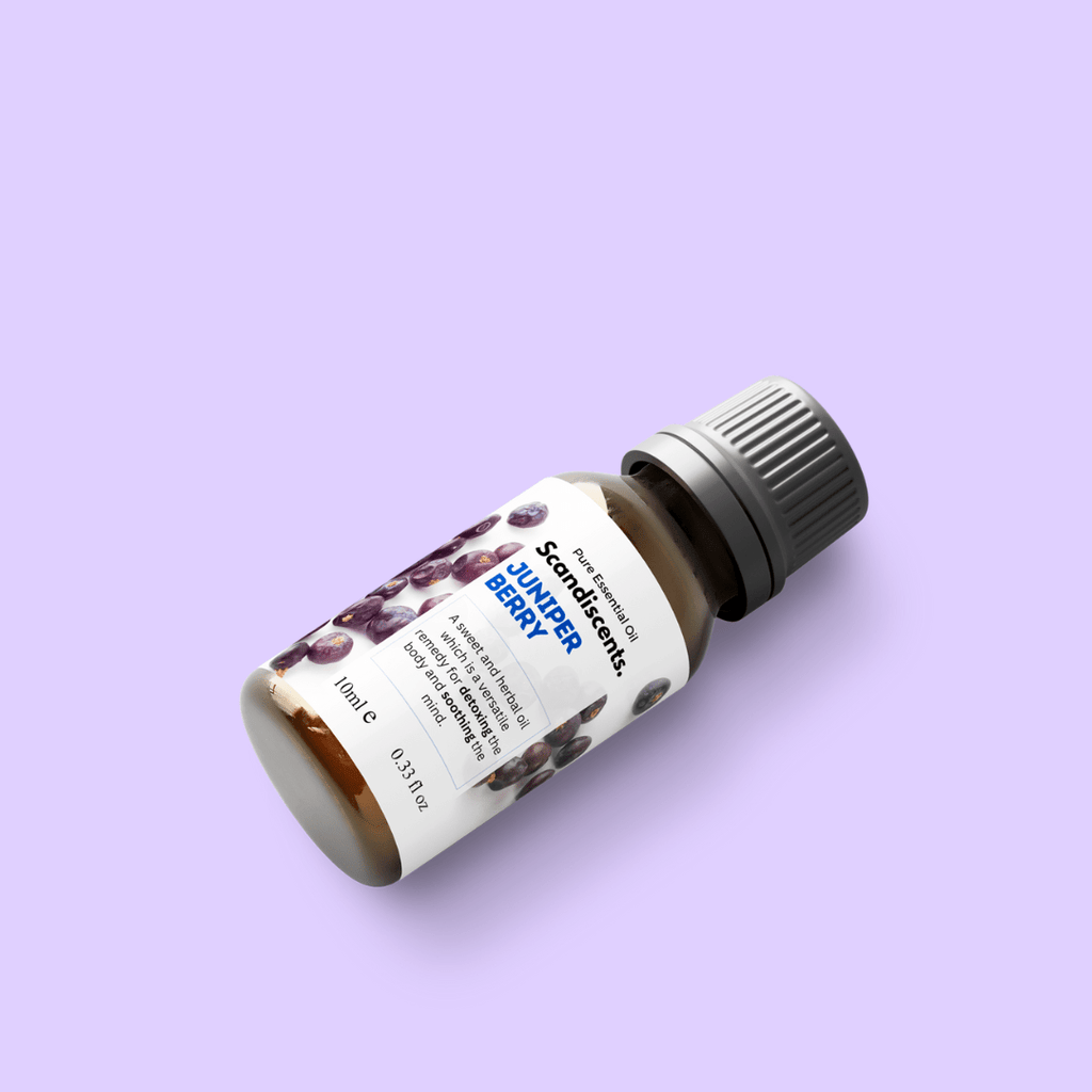 Scandiscents juniper berry essential oil bottle and fresh juniper berries on a wooden surface, highlighting natural botanical ingredients.