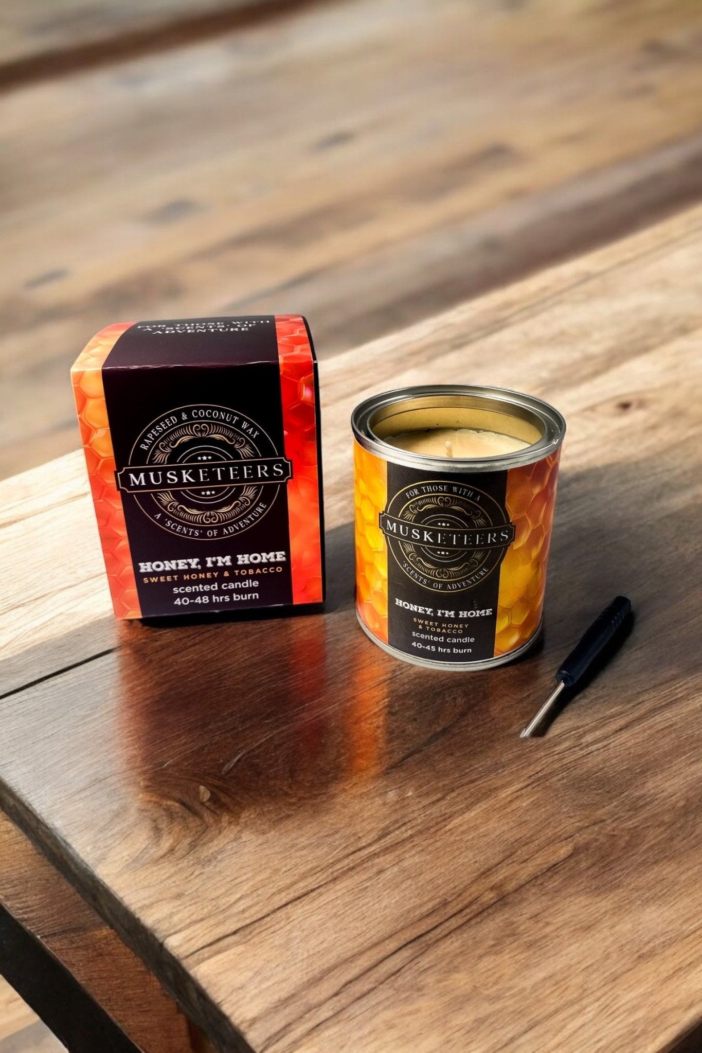 Musketeers Honey I'm Home candle with honey and tobacco scent, showing a beige candle in a glass jar with a wick.