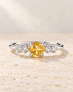 Sterling silver ring with a golden citrine centre stone and four clear accent stones on pale travertine.