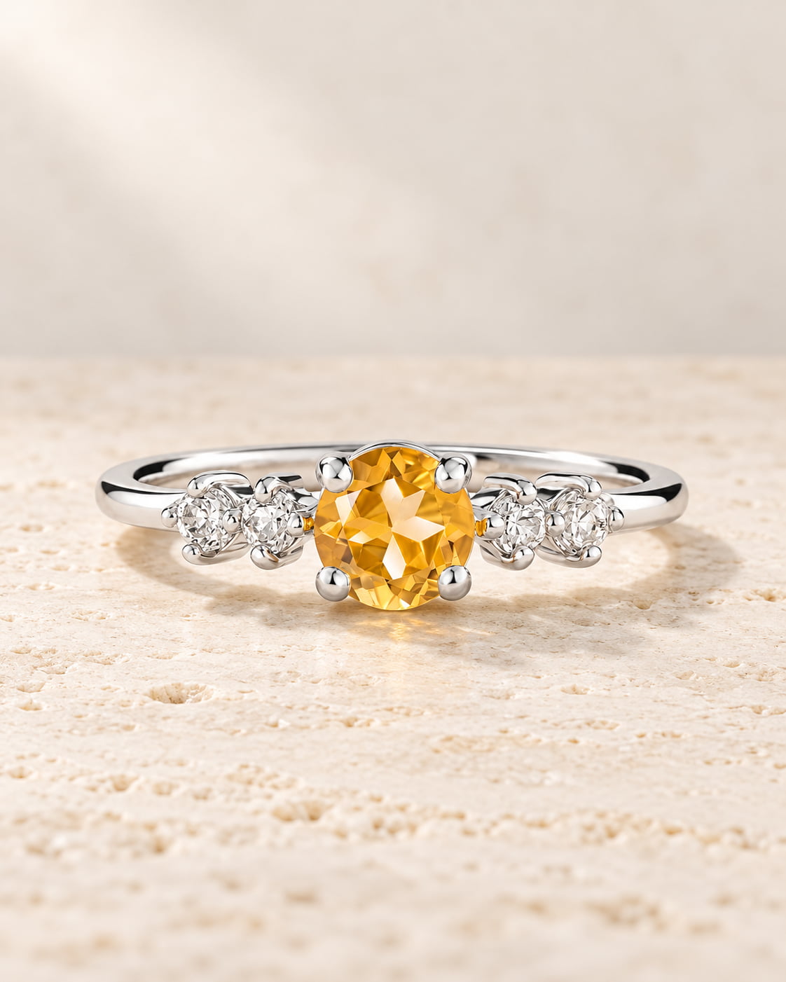 Sterling silver ring with a golden citrine centre stone and four clear accent stones on pale travertine.