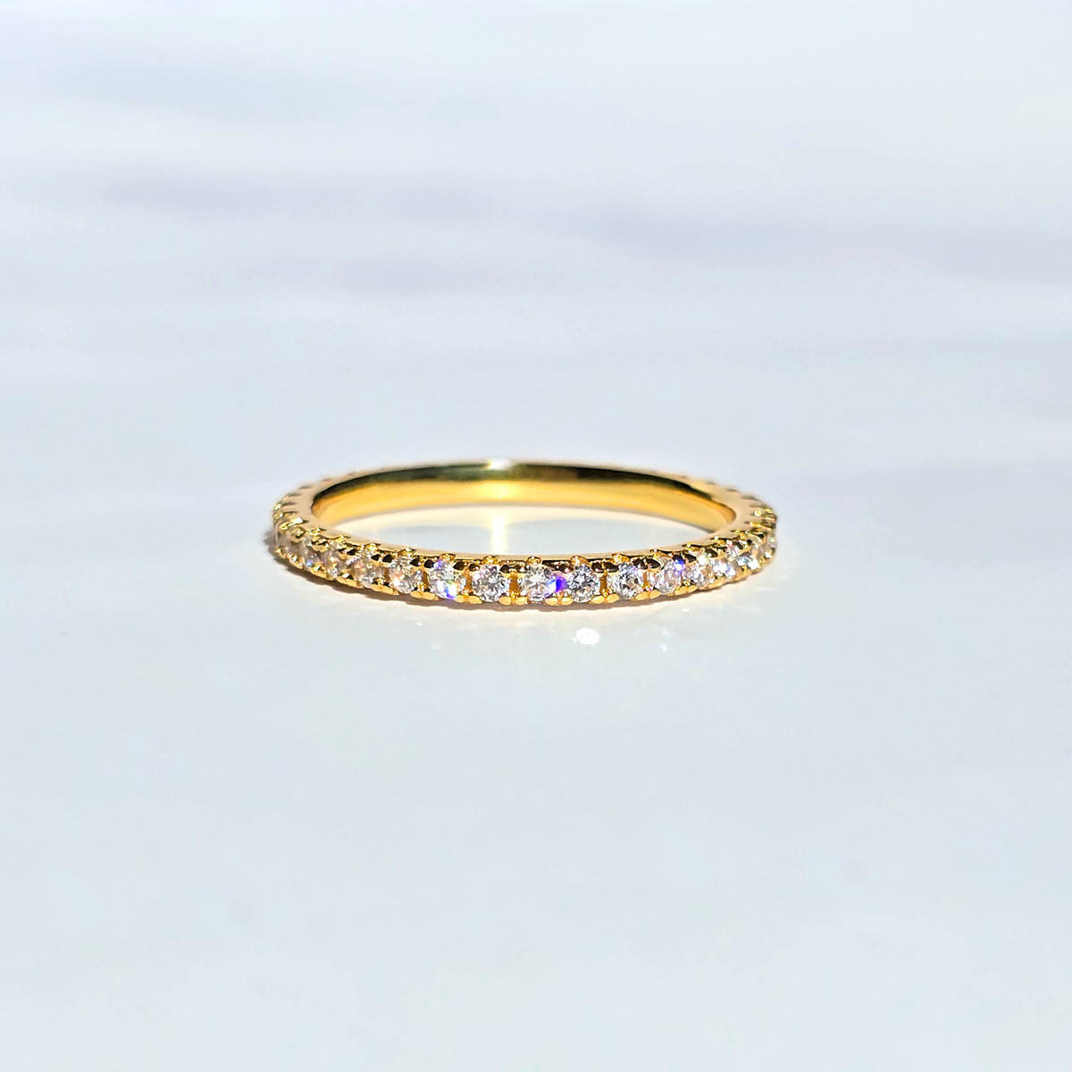 Gold ring with small diamonds on a light gray background