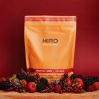 Hiro Essential Woman + Collagen superblend with mixed fruits, vibrant colorful blend in a clear glass jar.