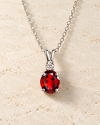 Sterling silver garnet pendant necklace on ivory travertine background, showcasing a Vianne Jewellery elegant gemstone pendant.