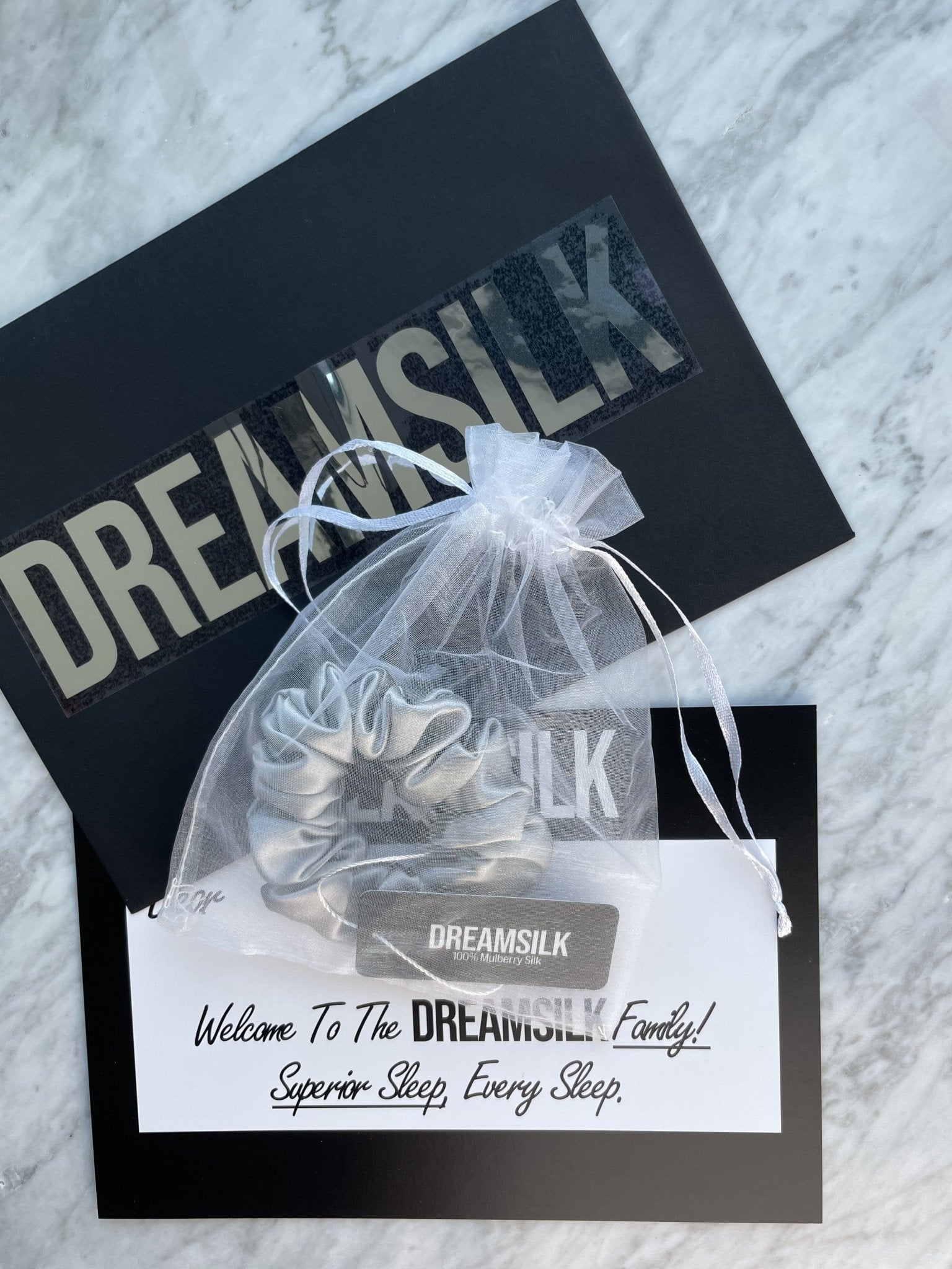 Silver silk scrunchie by DREAMSILK, showcasing a soft, shiny fabric hair accessory with gentle elastic for regular fit.