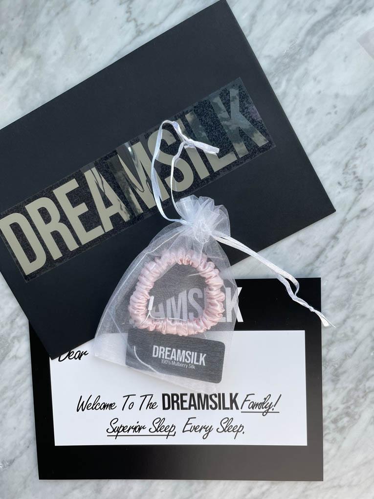Pink silk skinny scrunchie from DREAMSILK, soft and smooth hair accessory, shown on a white background.