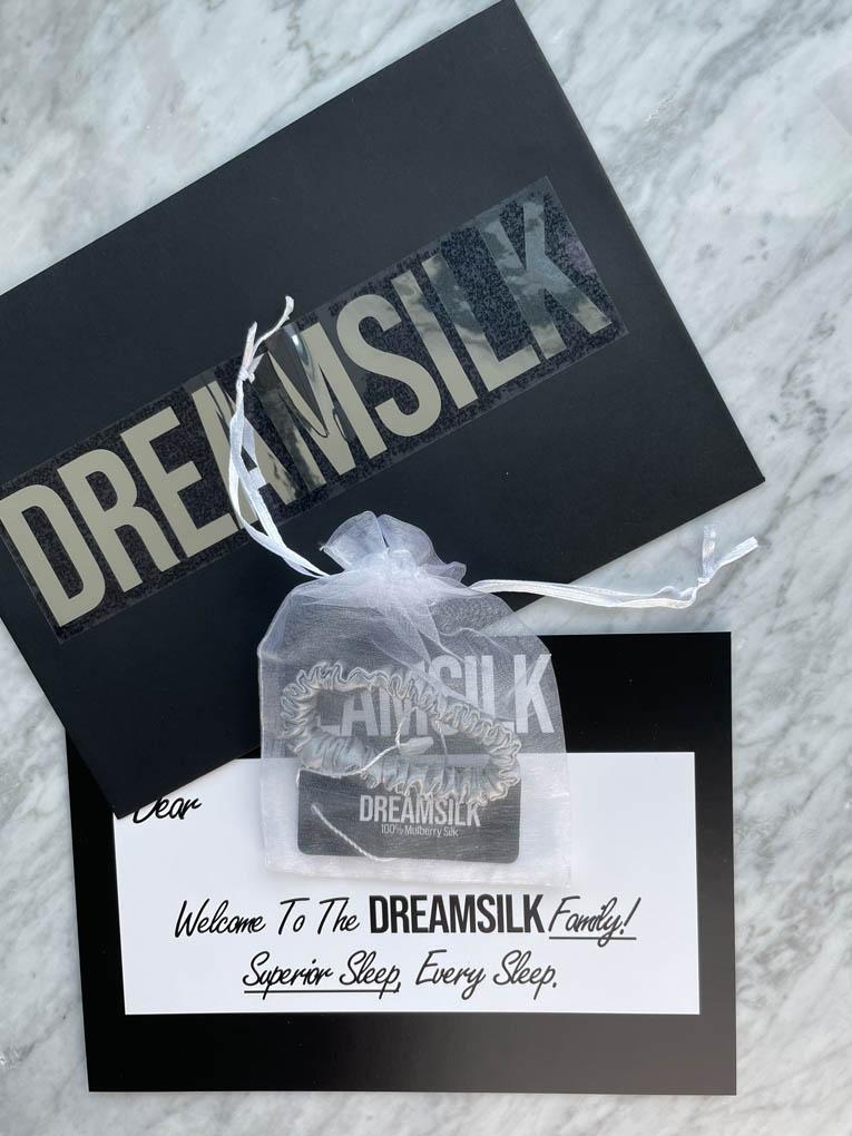 Silver silk scrunchie by DREAMSILK, showing a slim, shiny silk hair accessory on a neutral background.