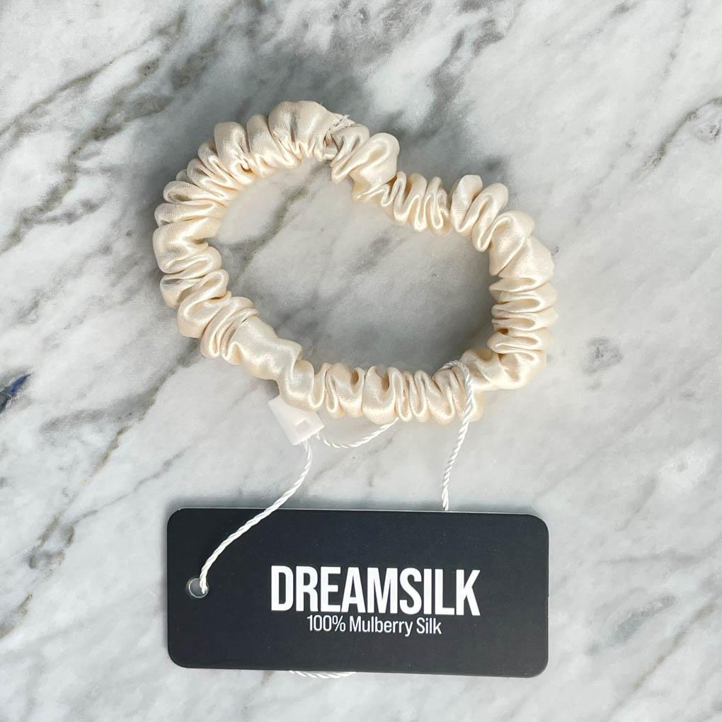 DREAMSILK champagne-colored silk skinny scrunchie showing smooth, shiny fabric and slim design for gentle hair styling.