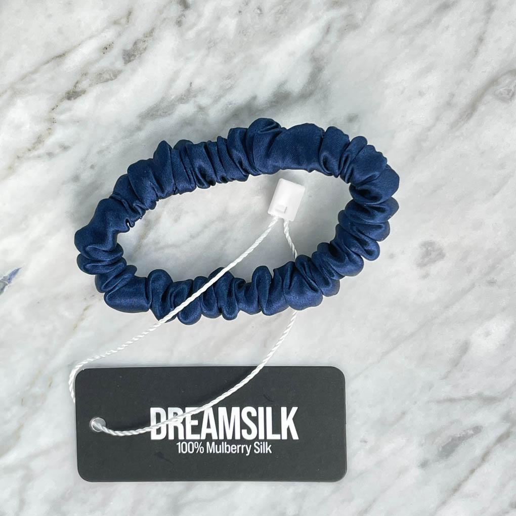 Navy blue silk skinny scrunchie from DREAMSILK with smooth, shiny fabric, ideal for stylish hair accessories.