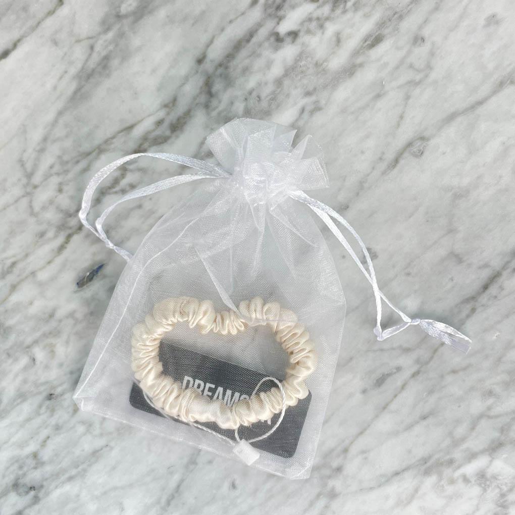 DREAMSILK champagne-colored silk scrunchie with a skinny design, soft and smooth for gentle hair styling.