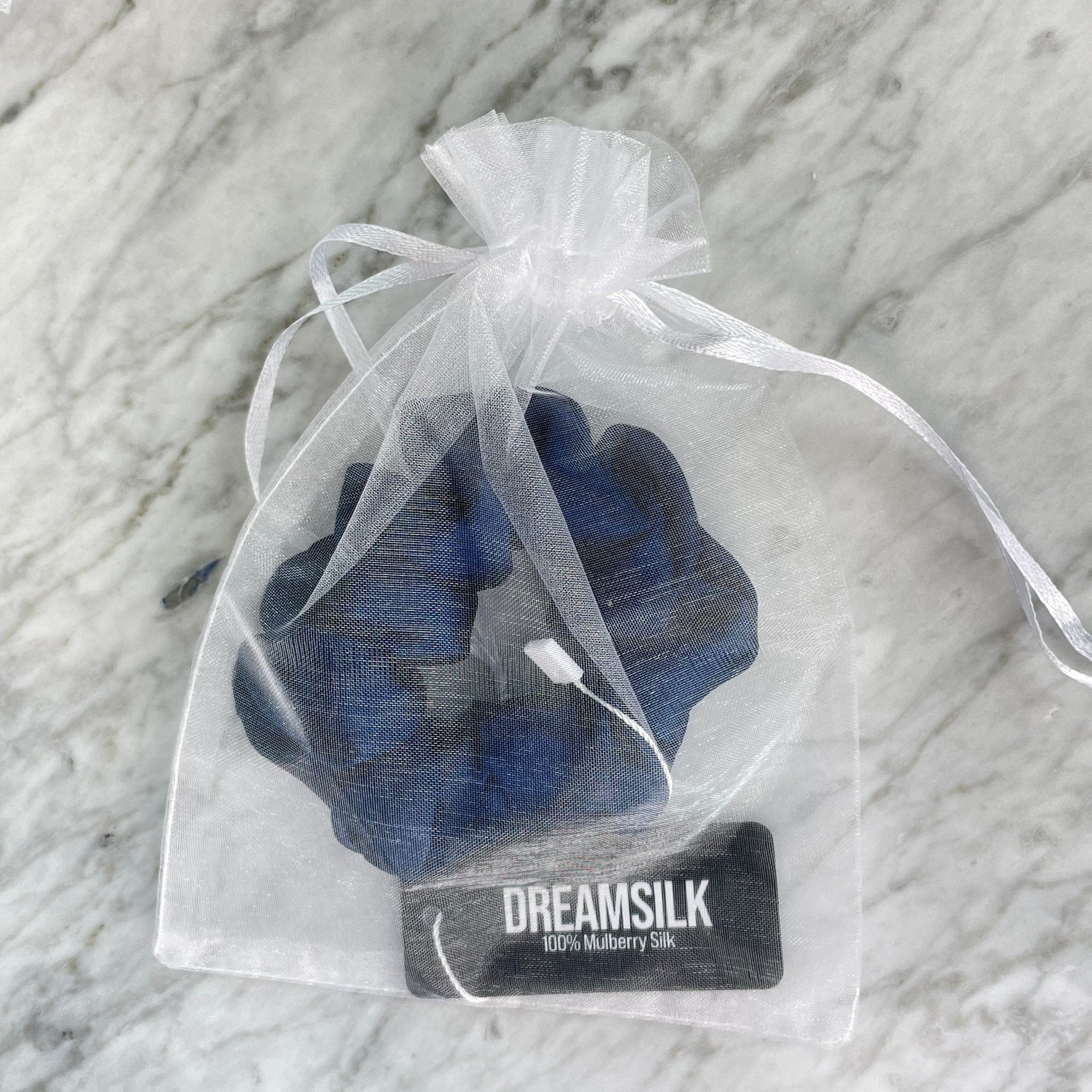 Navy blue silk scrunchie by DREAMSILK with a smooth, shiny fabric and elastic band for gentle hair styling.