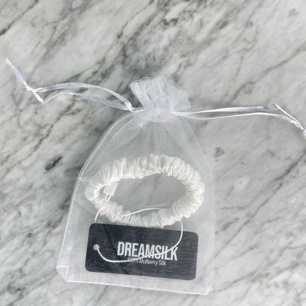 White silk skinny scrunchie from DREAMSILK, soft and smooth hair accessory shown on a plain background.