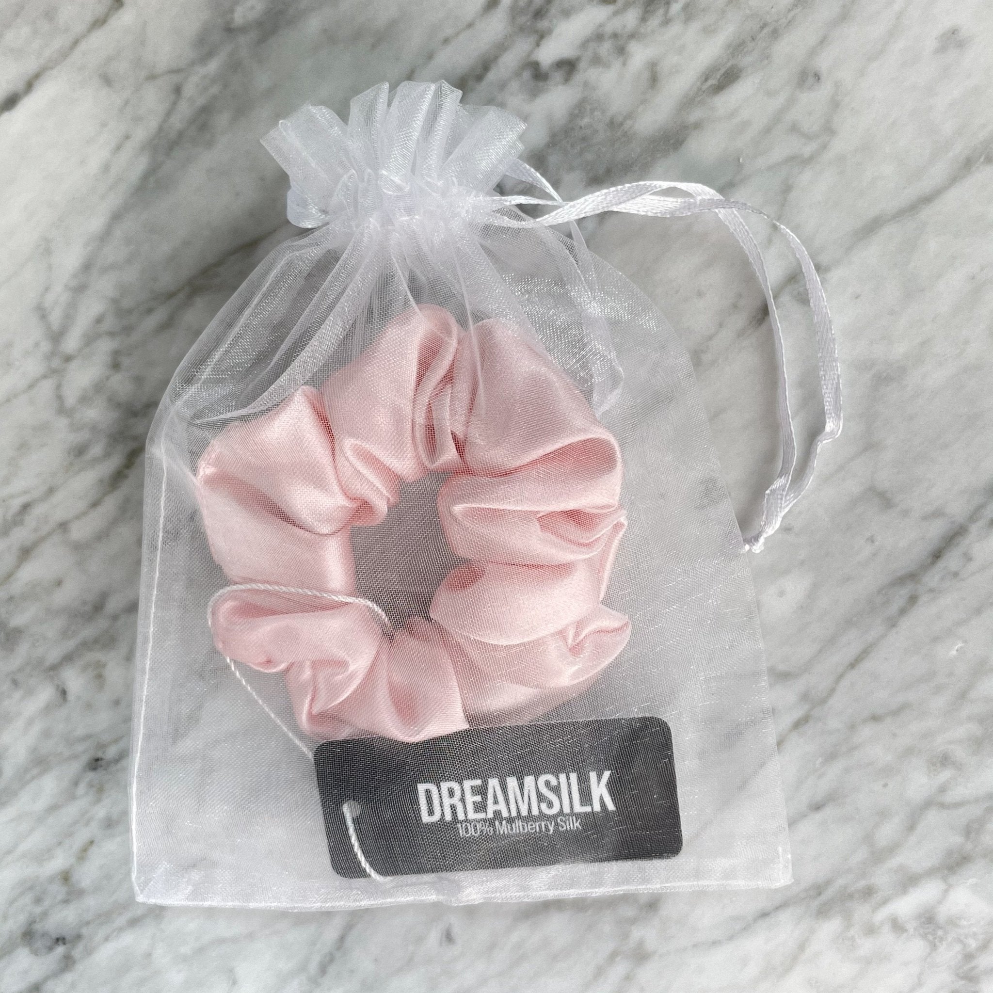 Pink silk scrunchie by DREAMSILK, regular size, shown wrapped around hair with smooth, shiny silk fabric.
