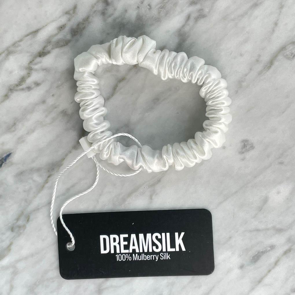 White silk skinny scrunchie by DREAMSILK, showing smooth, shiny silk fabric and elastic band for hair styling.
