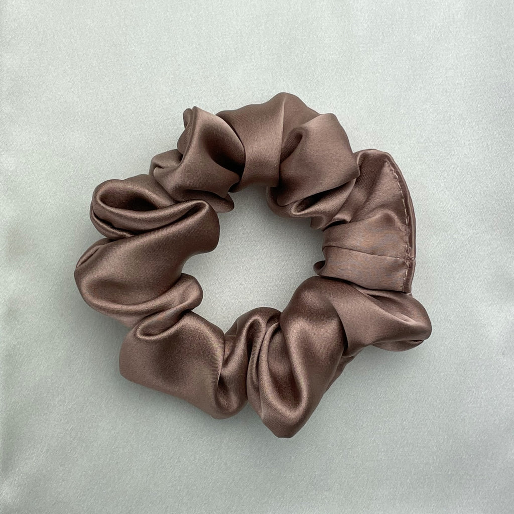 Bronze silk scrunchie by DREAMSILK with a smooth, shiny fabric and elastic band, perfect for gentle hair styling.