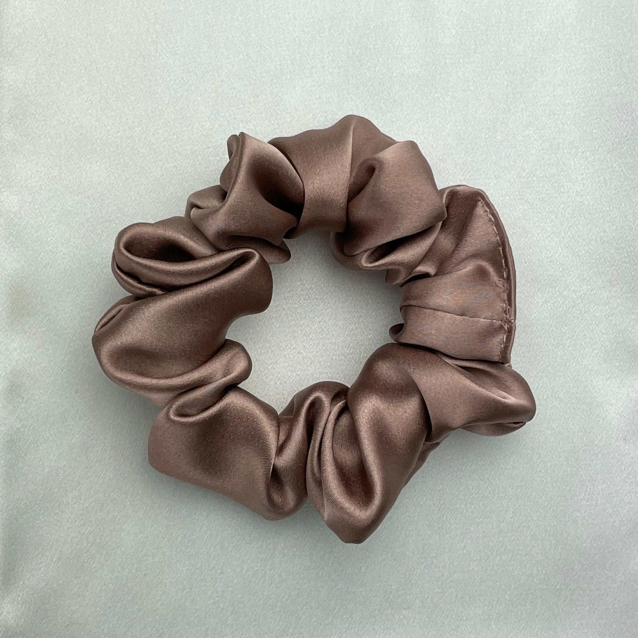Bronze silk scrunchie by DREAMSILK with a smooth, shiny fabric and elastic band, perfect for gentle hair styling.