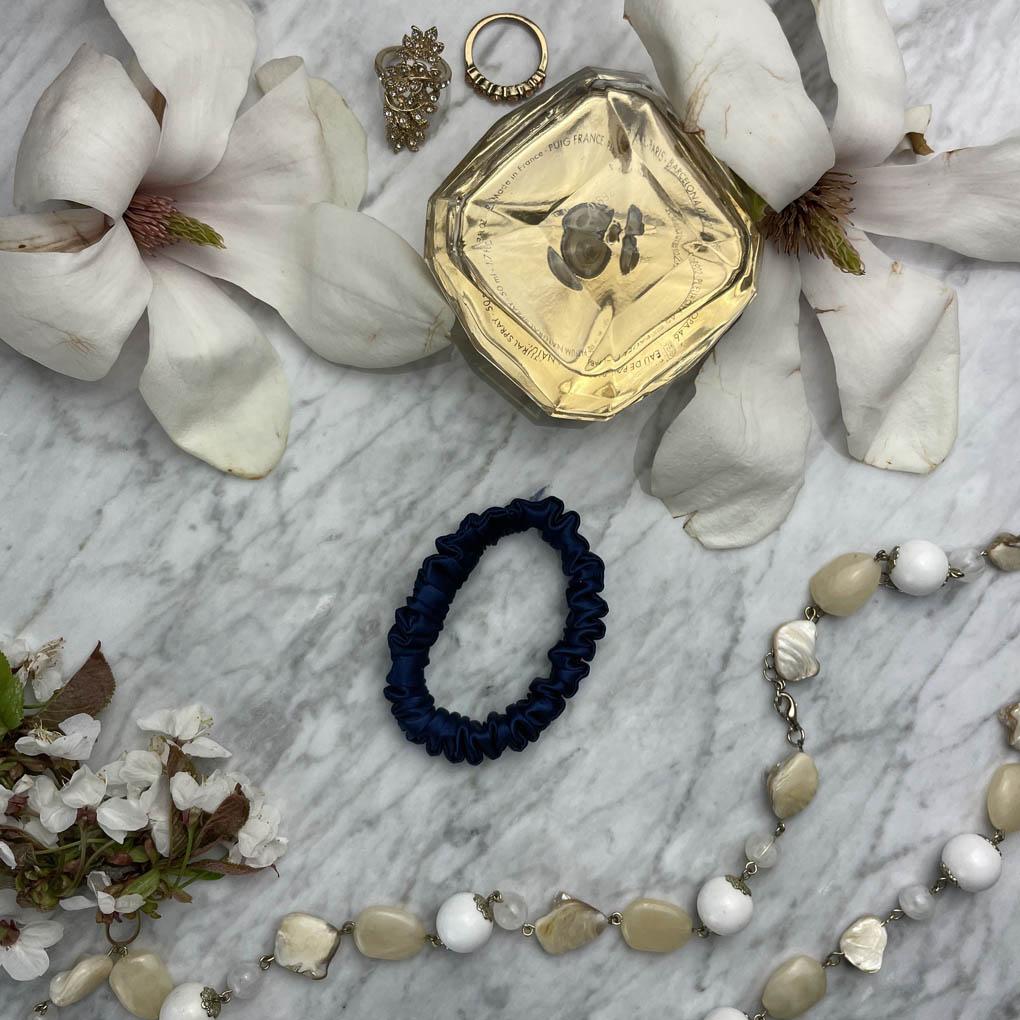 Navy blue silk skinny scrunchie from DREAMSILK with smooth, shiny fabric, ideal for securing hair with elegance.