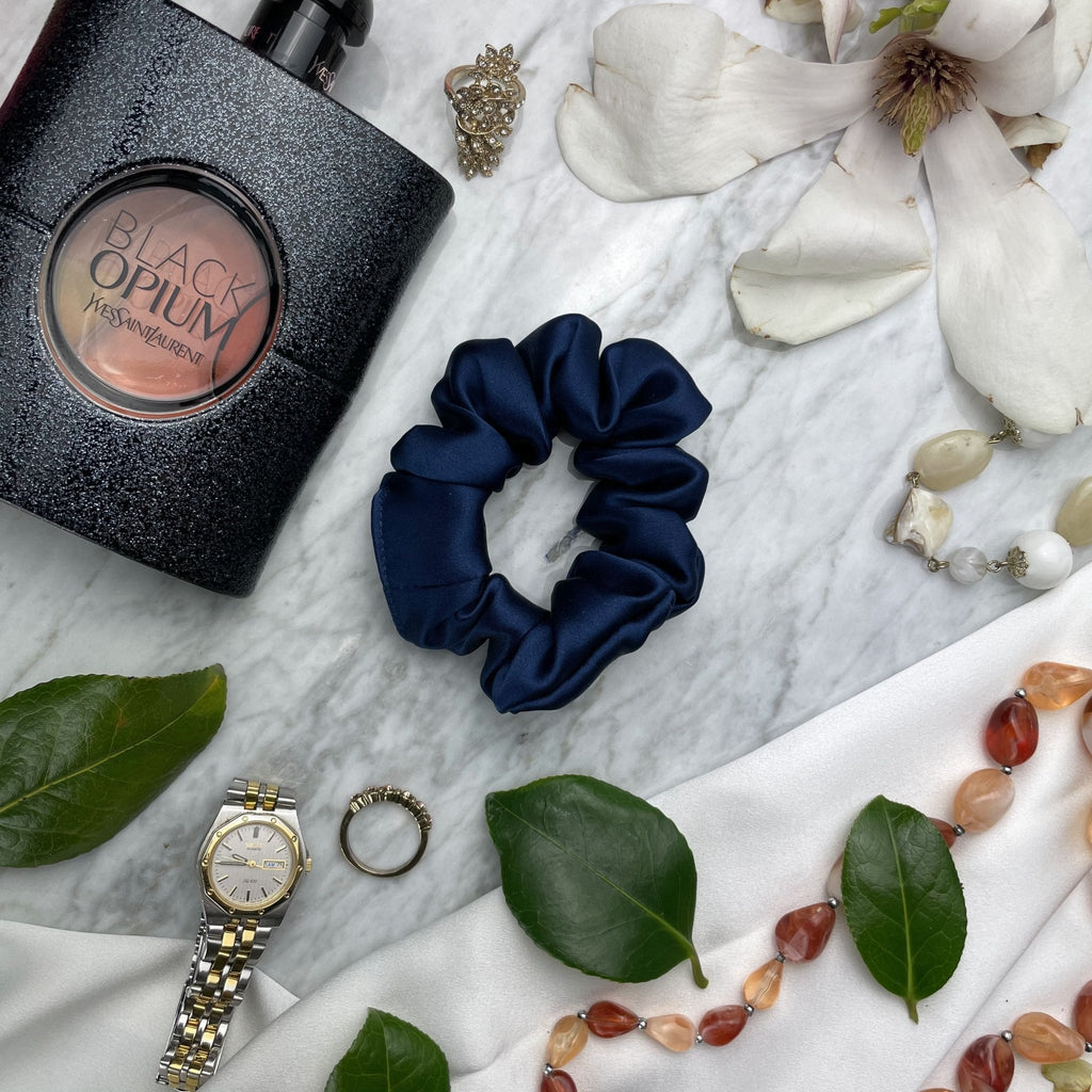 Navy blue silk scrunchie from DREAMSILK with a smooth, shiny texture, designed for gentle hair hold.