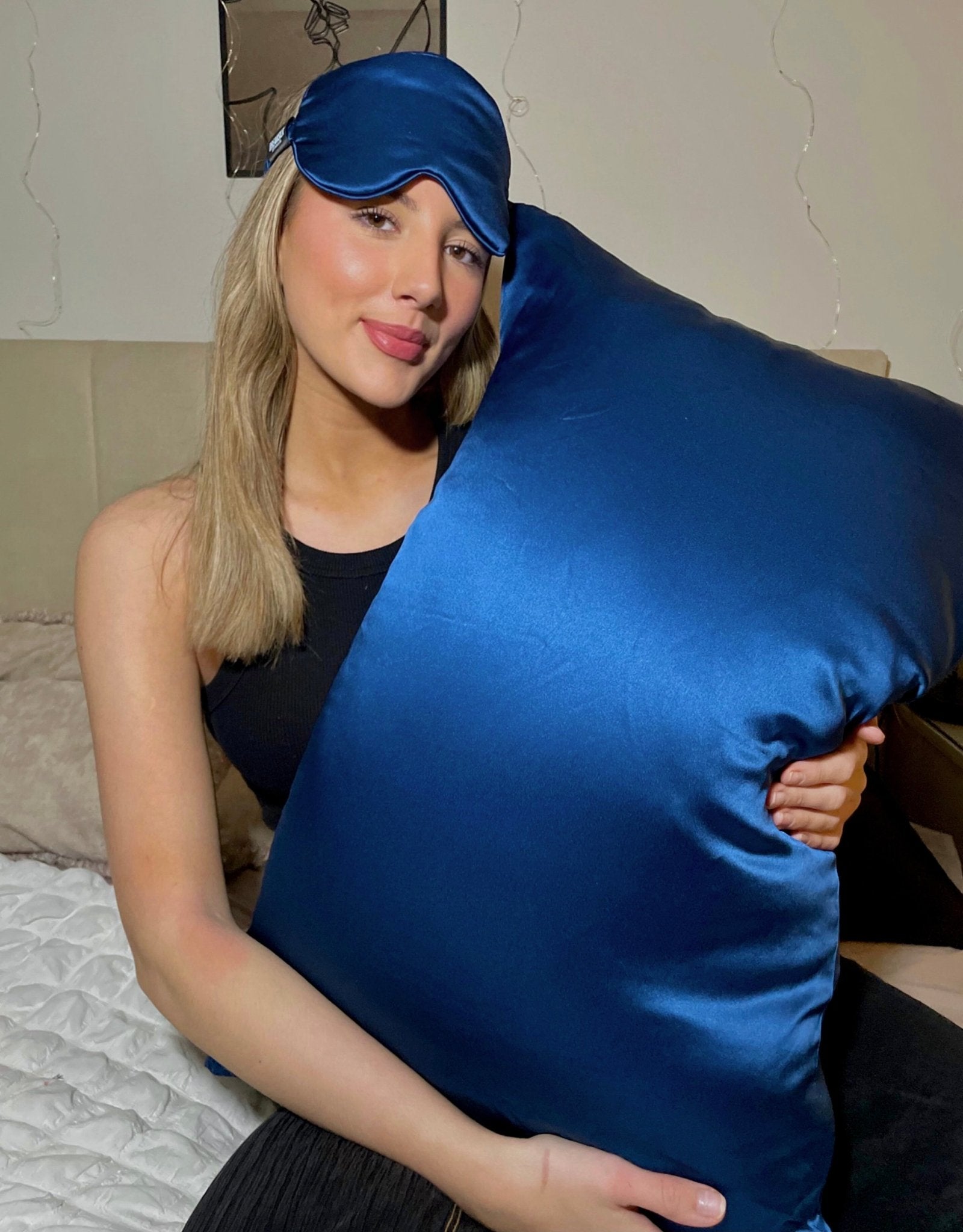 Navy blue silk pillowcase from DREAMSILK, standard size, smooth and luxurious fabric, shown on a bed with soft folds.