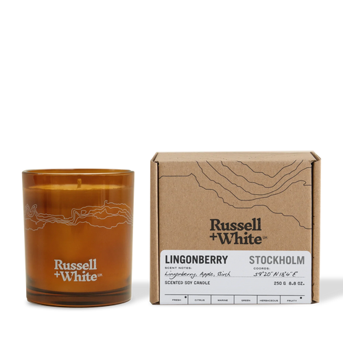 Russell + White scented soy candle in Lingonberry flavor, 250g, with a glass jar and lit wick, emitting a warm, cozy glow.