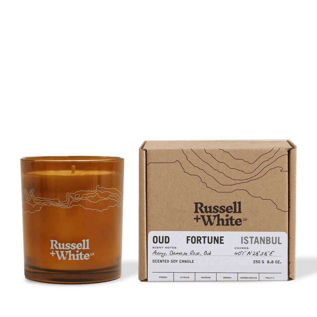 Russell + White Oud Fortune scented soy candle in 250g jar with warm amber-colored wax and elegant label design.