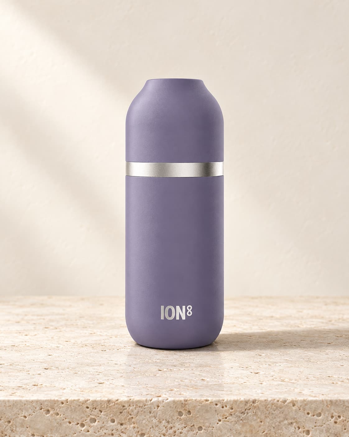 Purple ION8 Luma flask with a silver band standing on pale travertine against an ivory background.