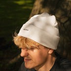White Uggly and Co beanie featuring a soft knit fabric, styled on a mannequin head. Perfect for casual winter wear.