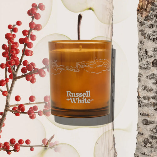 Russell + White Lingonberry scented soy candle in a glass jar with a wooden lid, showcasing a cozy, aromatic candle design.