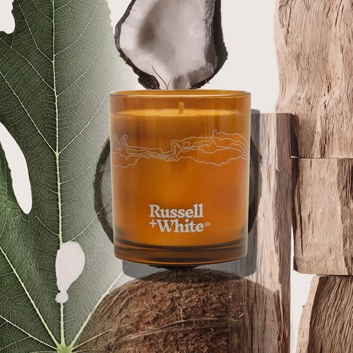 Russell + White Opulence scented soy candle in 250g jar, showcasing elegant packaging and a warm, inviting glow.