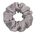 Silver silk scrunchie from DREAMSILK, showcasing a soft, shiny fabric hair accessory on a plain background.