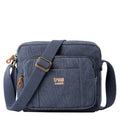 Blue Troop London across body bag with adjustable strap and front pocket, made of durable material.