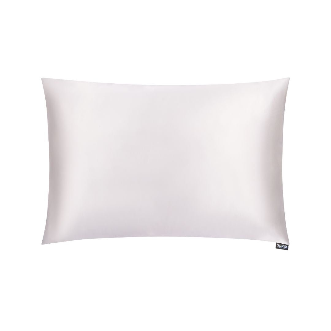 White silk pillowcase from DREAMSILK, standard size, smooth and luxurious fabric, displayed on a bed with soft lighting