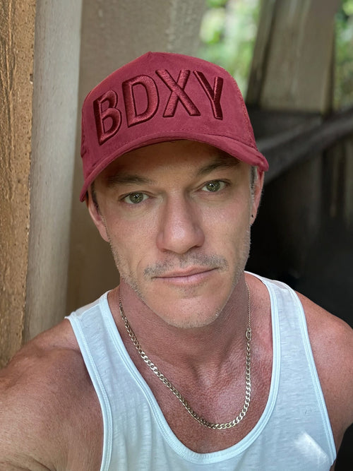 Burgundy trucker cap called "The Gaffer" by BDXY Studios, with mesh back and curved brim, displayed on a plain background.