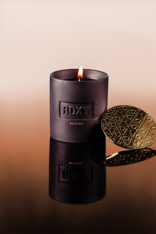 BDXY Studios Alfama scented candle with a white ceramic container and a lit wick, emitting warm ambient light.