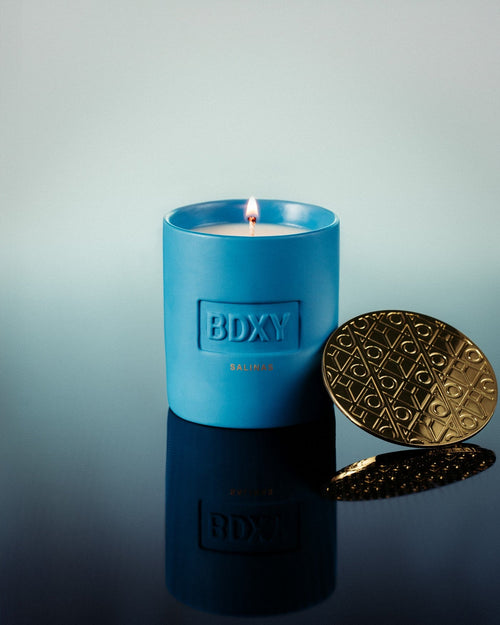 BDXY Studios scented candle with a white ceramic jar and floral design, emitting a warm glow and fresh floral fragrance.