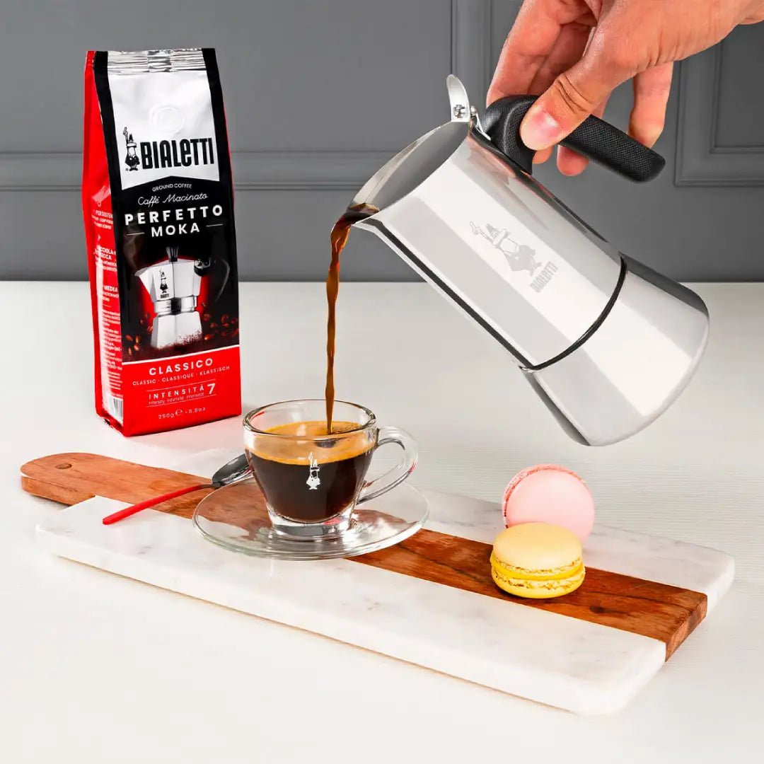 Bialetti Venus stovetop coffee maker on induction stove, showcasing its sleek aluminum design and handle for brewing espresso.
