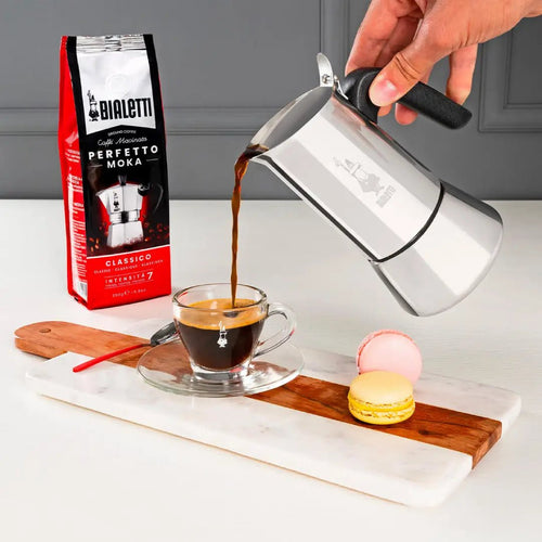 Bialetti Venus stovetop coffee maker on induction stove, showcasing its sleek aluminum design and handle for brewing espresso.