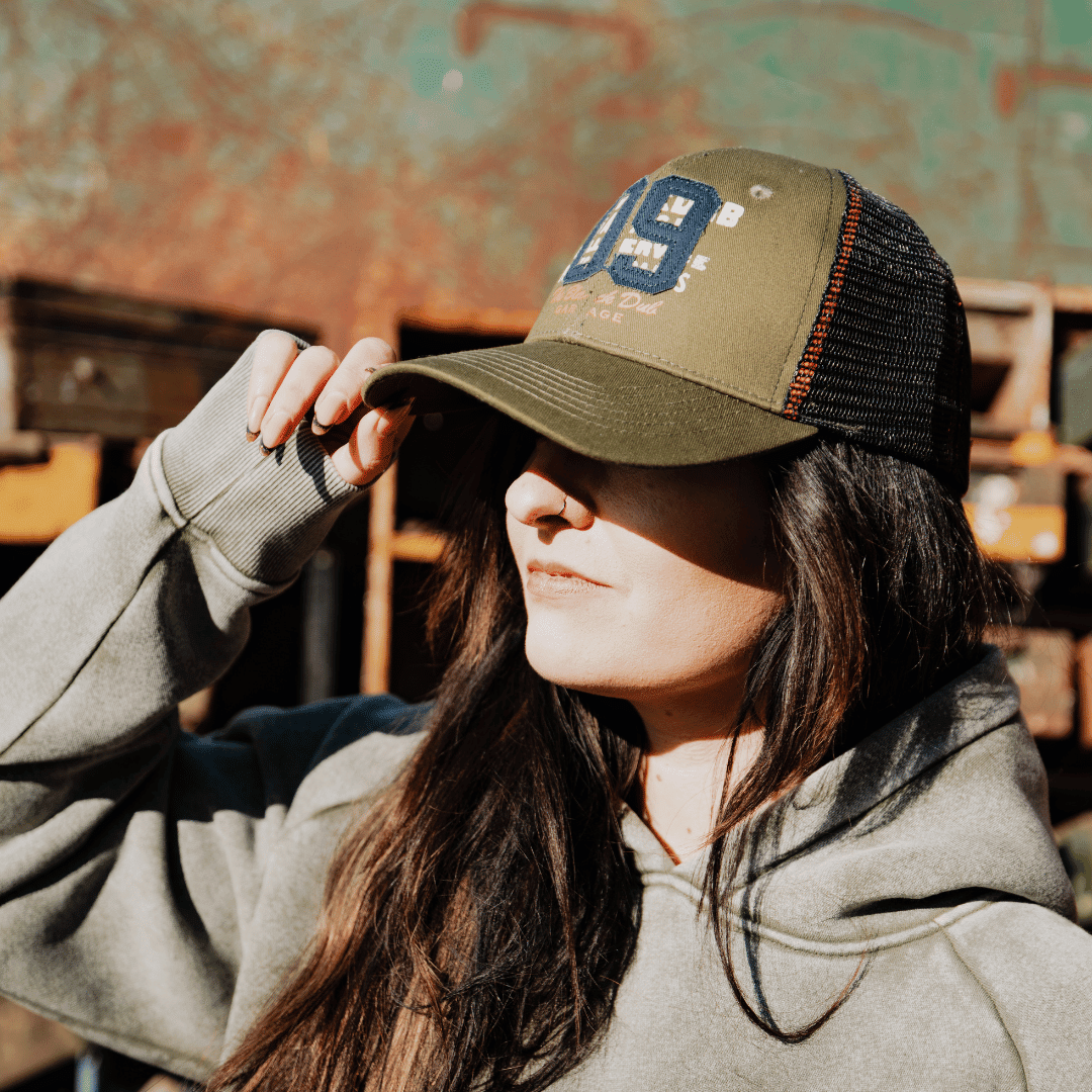 Green trucker cap with '09' logo from Uggly and Co, featuring mesh back and adjustable strap, in a casual biker style.