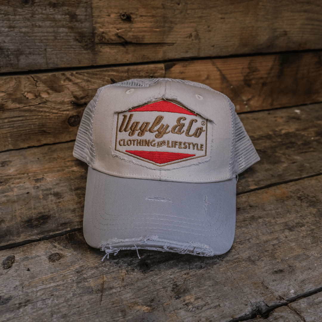Silver and grey diamond-patterned Uggly and Co trucker cap featuring a classic mesh back and front logo design.