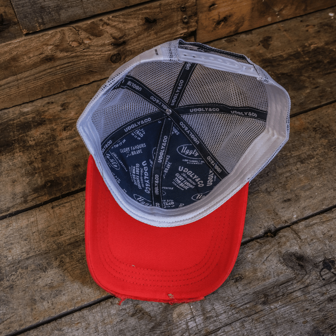 Blue and red diamond pattern trucker cap by Uggly and Co, featuring a classic mesh back and adjustable snap closure.